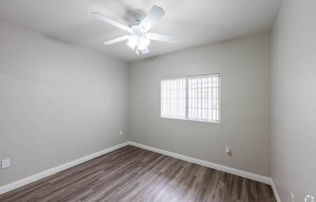 A room with a ceiling fan and wooden flooring.