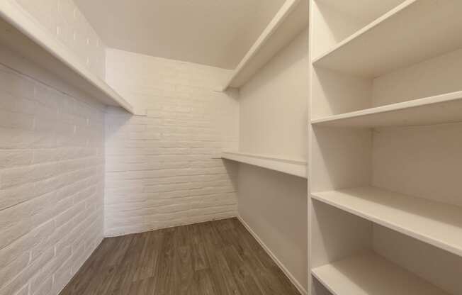 a room with white shelves and a white brick wall