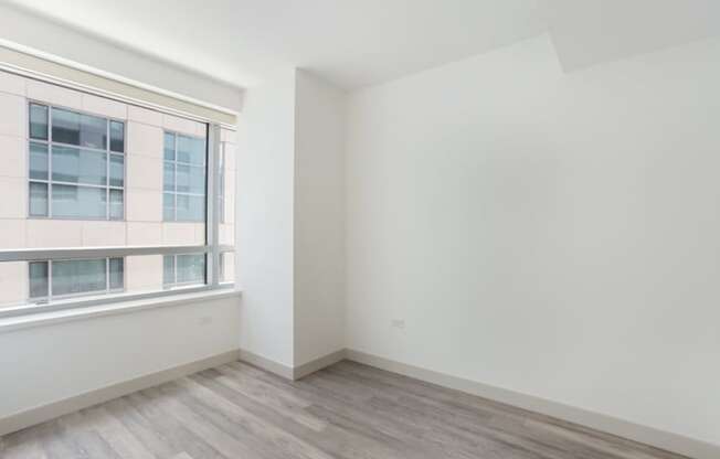 an empty room with a large window and white walls