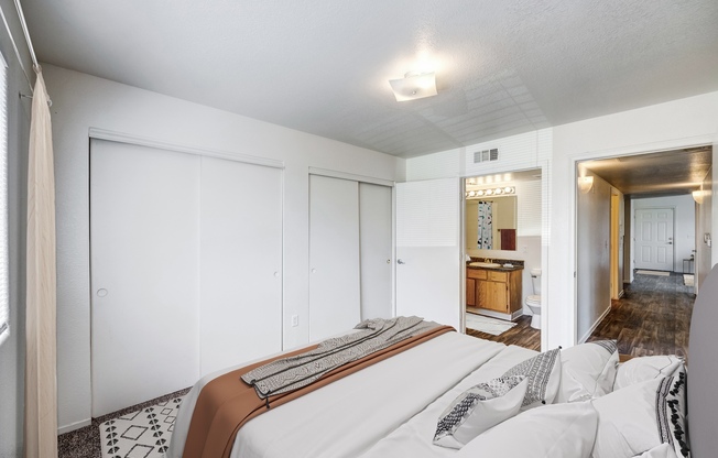 Two-Bedroom Apartments in North Las Vegas, NV - Portola Del Sol - Bedroom with Abstract Printed Bedding, Sliding Closet Doors, and Connected Bathroom