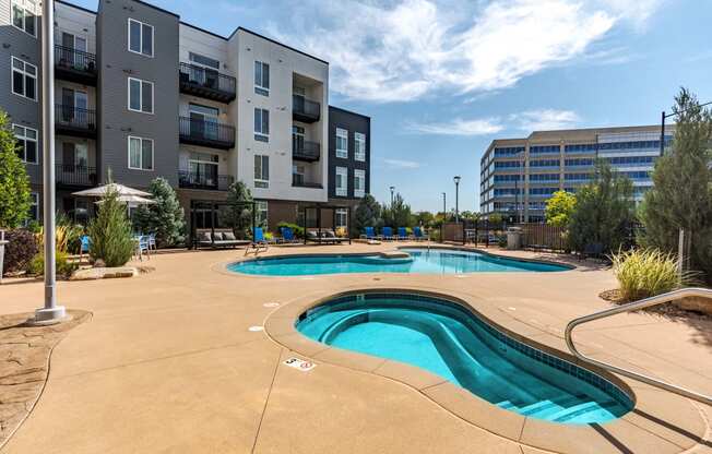 our apartments have a pool and hot tub with an apartment building in the background