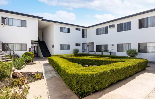 an exterior view of a building with hedges and a courtyard