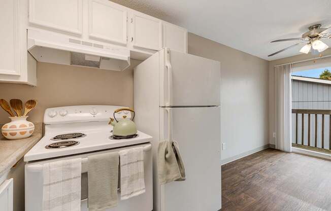 A kitchen with a white stove and a white refrigerator with a white wall and a white ceiling.