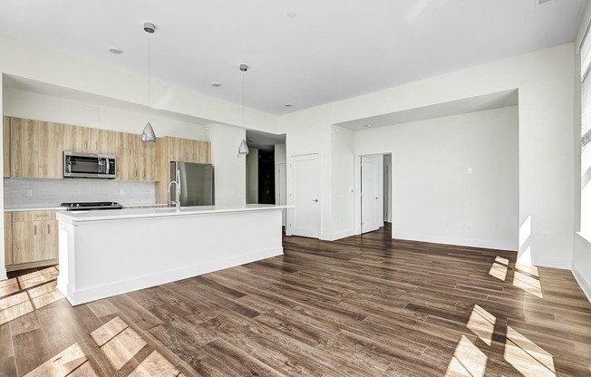 A spacious living room with a wooden floor and white walls.