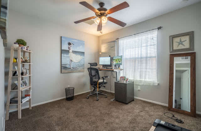 A room with a ceiling fan and a painting of a woman on the wall.