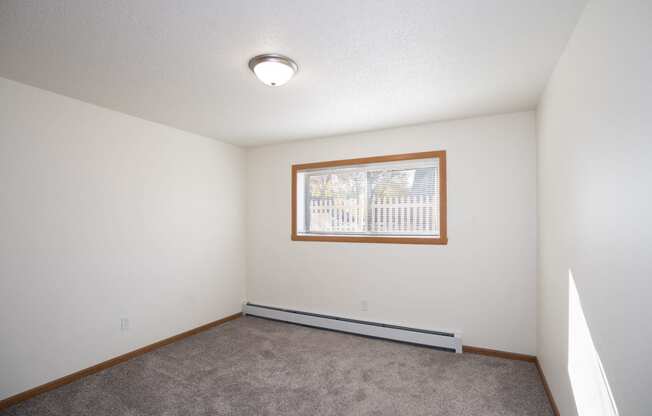 an empty living room with carpet and a window. Fargo, ND Country Club Apartments