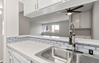 White tiled kitchen with stainless steel farmhouse style sink.