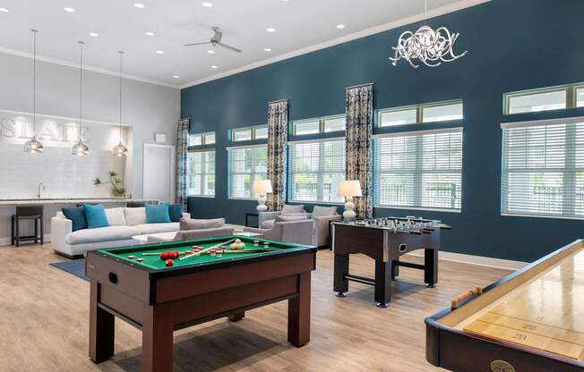 A billiards table is in the middle of a room with a pool table on the right.