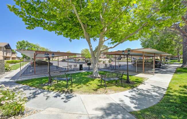 a park with trees and benches and a fenced in area