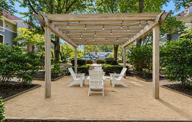 A wooden pergola with four chairs underneath it.