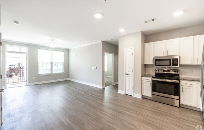 an empty kitchen and living room with a stove and microwave