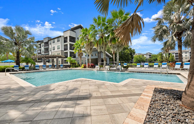 a swimming pool with palm trees and buildings in the background