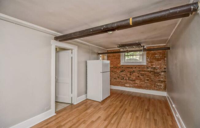 Living area with wood-like flooring and exposed brick wall