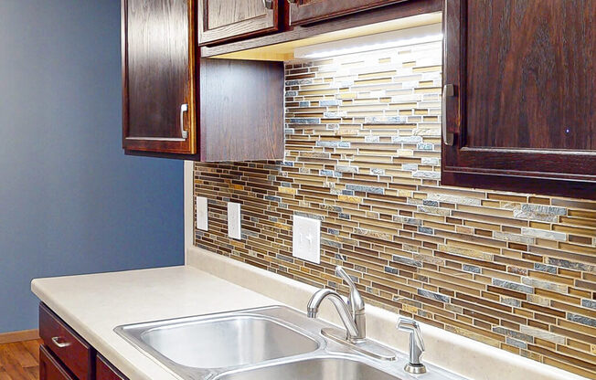 A kitchen with a sink and a backsplash made of tiles.