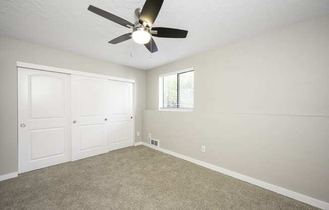 a bedroom with a ceiling fan and two closets