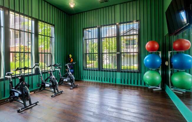 the gym at the colony house is equipped with exercise equipment and windows