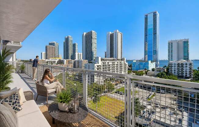 A woman is sitting on a balcony with a view of a city skyline.
