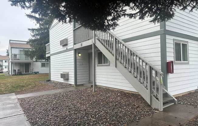 A white house with a grey staircase leading to the front door.