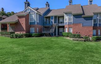 a large brick building with green grass in front of a house