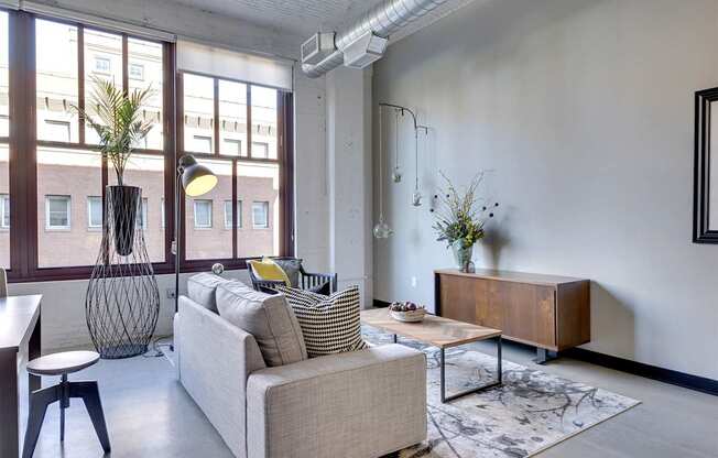 A living room with a couch, a chair, a table, and a vase with flowers.