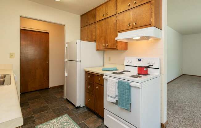 a kitchen with white appliances and wooden cabinets and a white refrigerator. Fargo, ND Islander Apartments