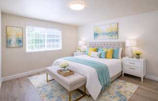 A bedroom with a white bed and a blue and yellow throw blanket.