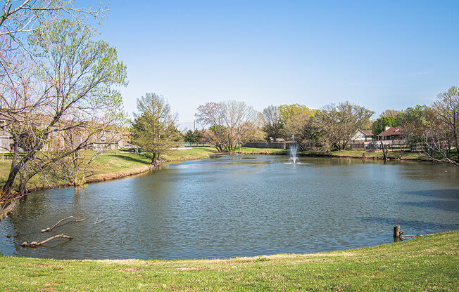 A lake in a park with a fountain in the middle.
