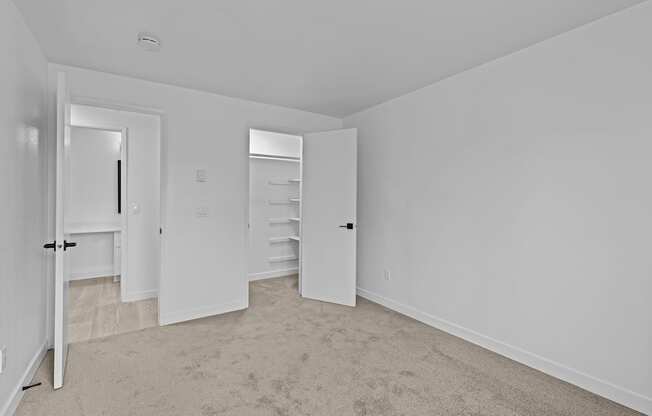 an empty bedroom with white walls and a closet