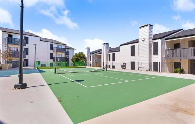 an outdoor tennis court with apartments in the background