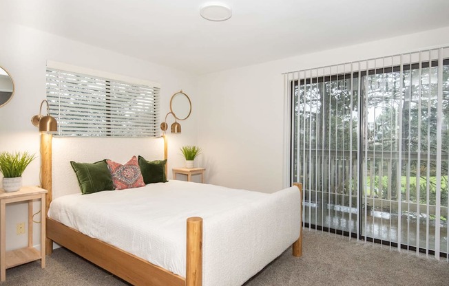 A bedroom with a bed, two lamps, and a window with blinds.