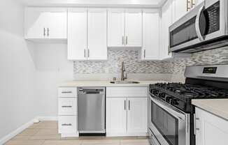 a white kitchen with stainless steel appliances and white cabinets at Hollywood Vista in Los Angeles, CA