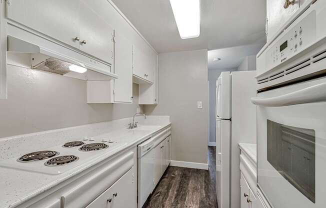 A white kitchen with a white stove top oven.