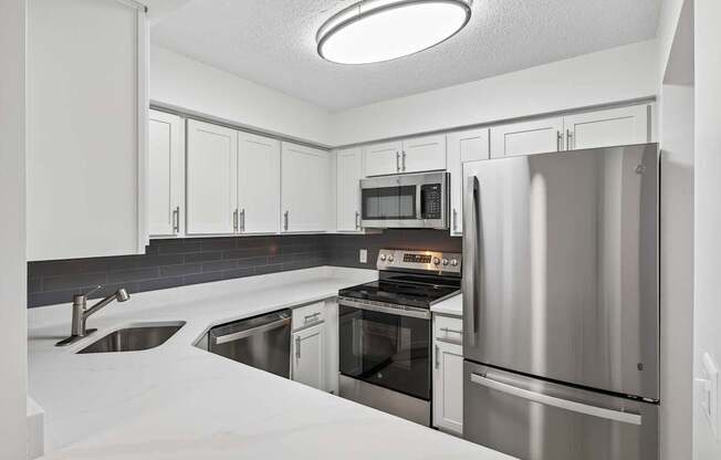 A modern kitchen with stainless steel appliances and white cabinetry.