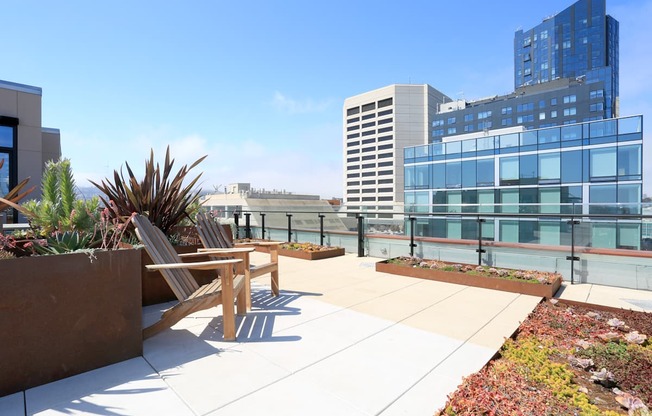 A rooftop patio with a table and chairs overlooking a cityscape.