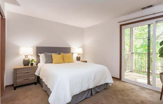 A bedroom with a bed, nightstand, and sliding glass doors.