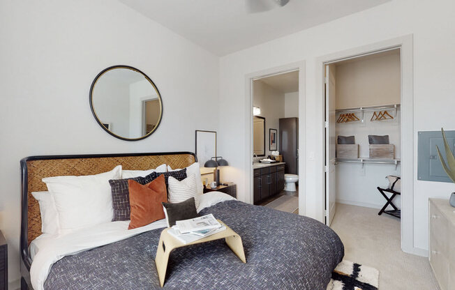 a bedroom with a large bed and a bathroom in the background