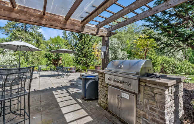 A BBQ grill is on a patio with a table and chairs.