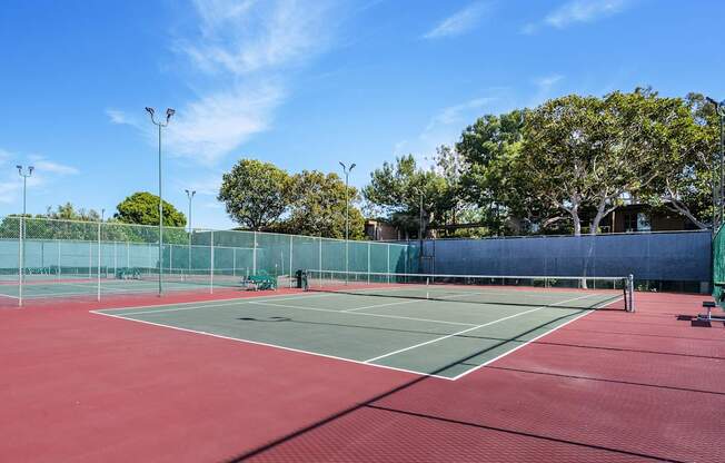 A tennis court with a red surface and green boundary wall at Mariners Village, Marina del Rey, 90292