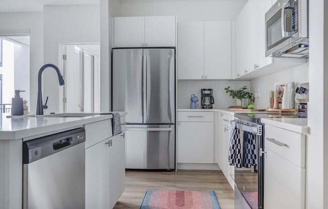 A modern kitchen with white cabinets and stainless steel appliances.