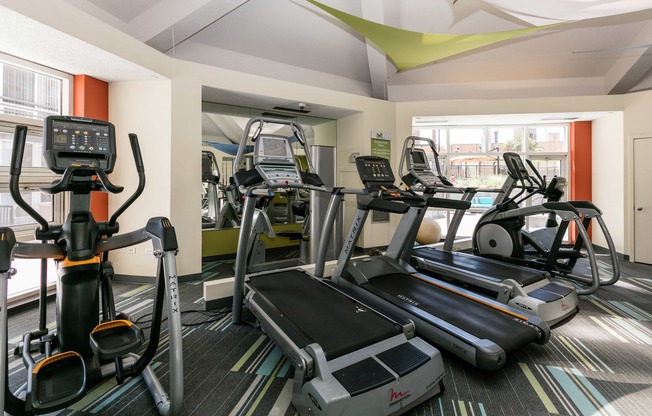 a gym with cardio equipment on the floor and a large window