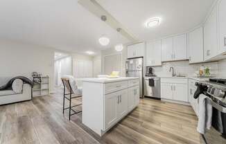 A modern kitchen with white cabinets and a wooden floor.