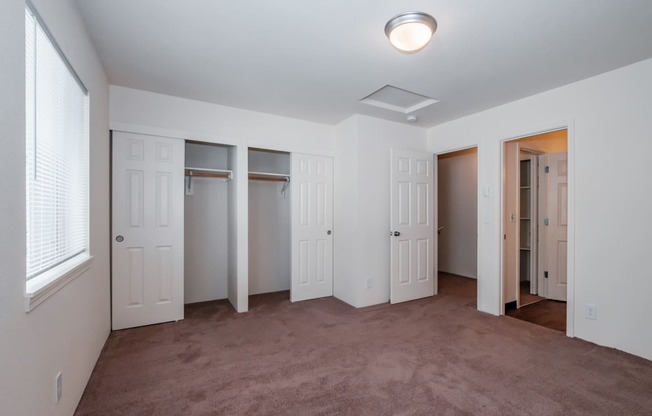 a bedroom with a carpeted floor and three closets