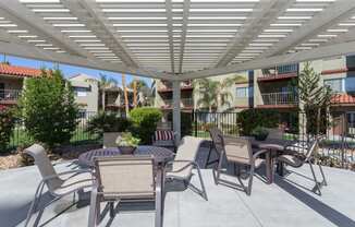 a patio with tables and chairs under a shade