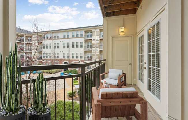 A balcony with a table and chairs overlooks a courtyard.
