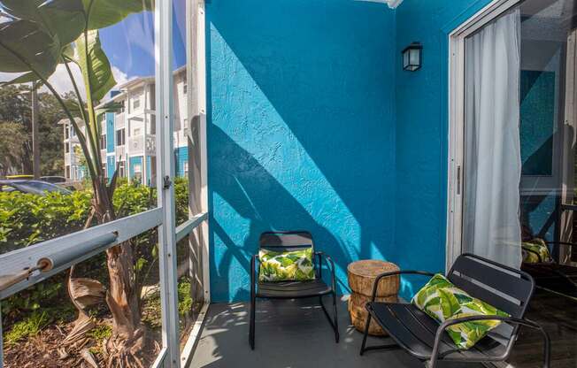 A blue wall with a white curtain and a black chair.