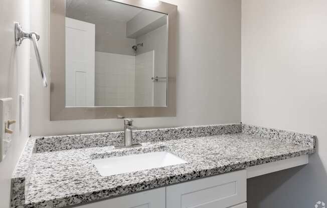 a bathroom with granite counter top and a sink and a mirror