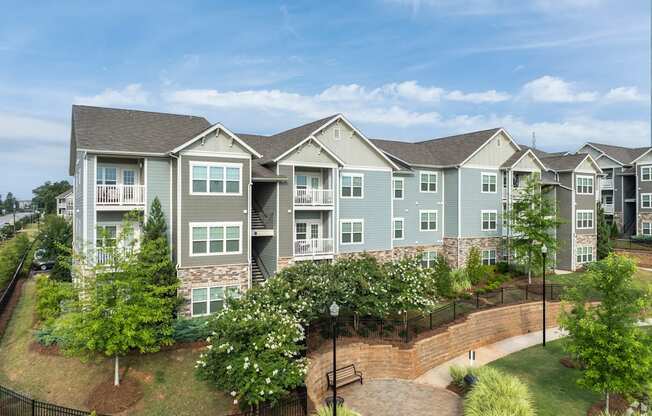 A large apartment complex with a black fence and a brick walkway.