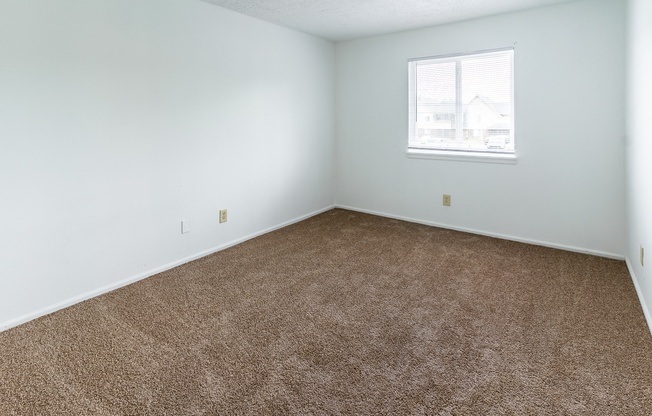 an empty room with carpet and a window