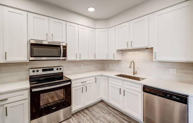 a kitchen with white cabinets and stainless steel appliances