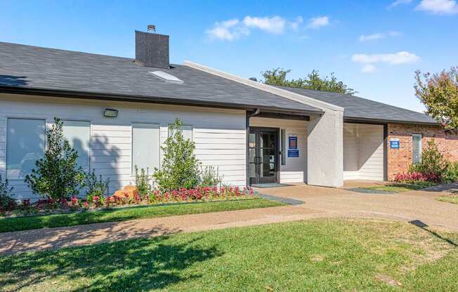 A small building with a grey roof and a white wall with a blue sign on it.